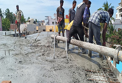 Workers spreading ready-mix concrete for floor construction